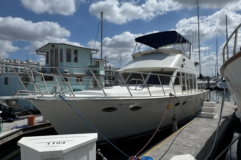 1999 McKinna 47 Sedan yacht docked at marina under cloudy sky.