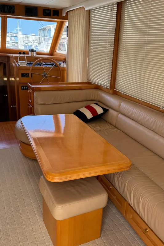Interior of 1999 McKinna 47 Sedan yacht with beige seating and wooden table.