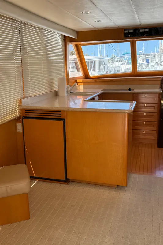 Interior of 1999 McKinna 47 Sedan yacht with wooden cabinetry and large windows.