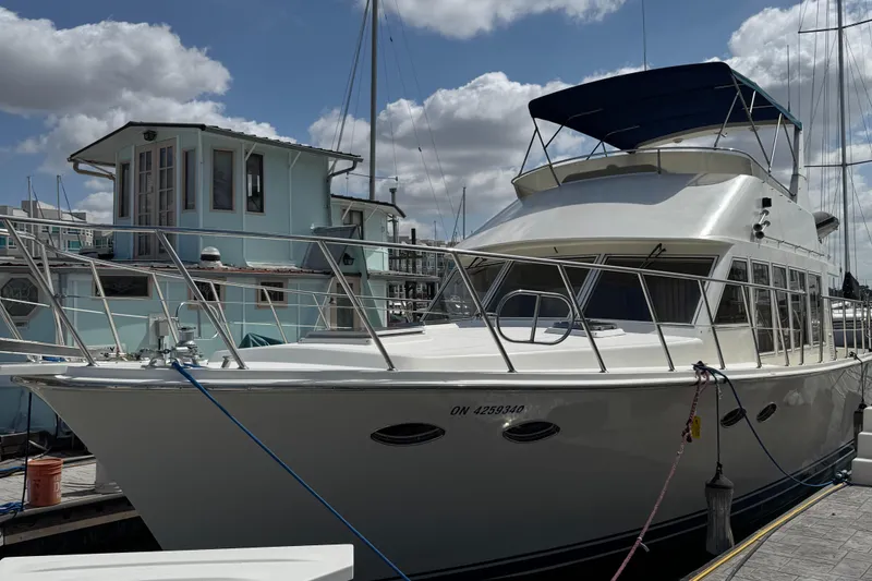 1999 McKinna 47 Sedan yacht docked at marina under cloudy sky.