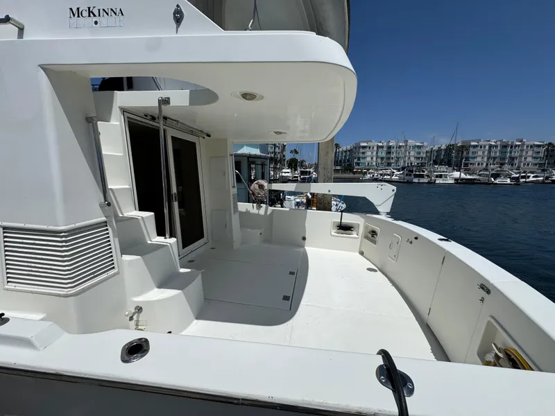 1999 McKinna 47 Sedan yacht docked at marina, showcasing spacious deck and sleek design.