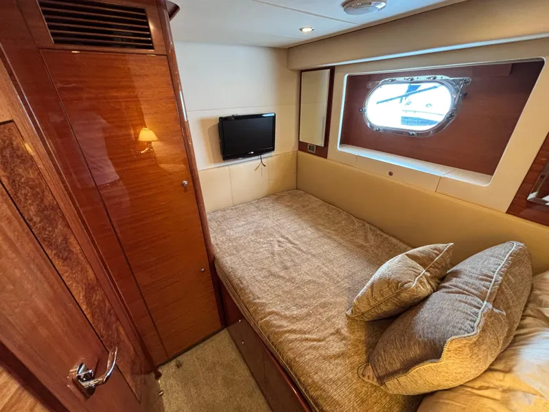 Cozy cabin interior of 2010 Norseman 80 yacht with bed, window, and TV.