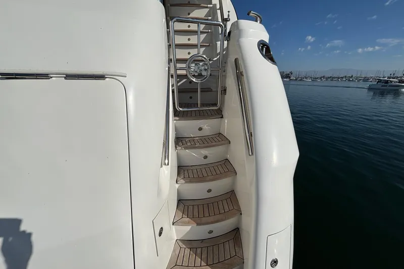 Staircase on 2010 Norseman 80 yacht with wooden steps, docked by calm waters.