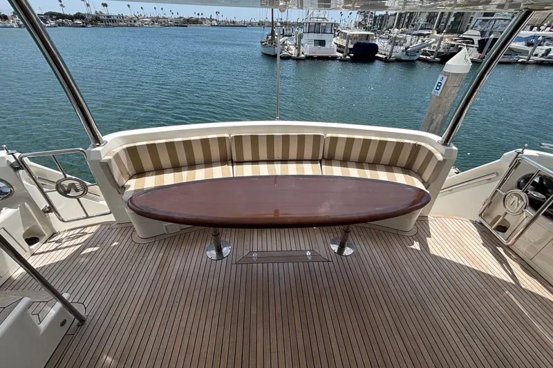 Luxurious 2010 Norseman 80 yacht deck with striped seating and oval table, overlooking marina.