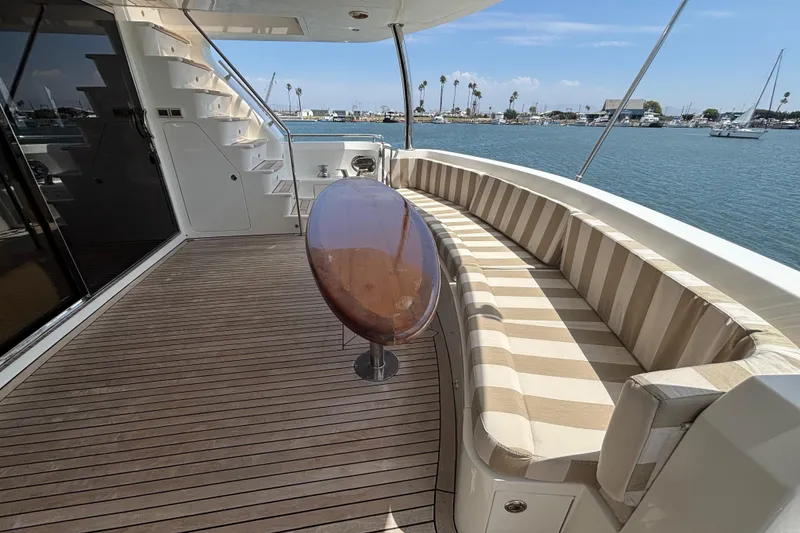 Luxury Norseman 80 yacht deck with striped seating, wooden table, and ocean view.