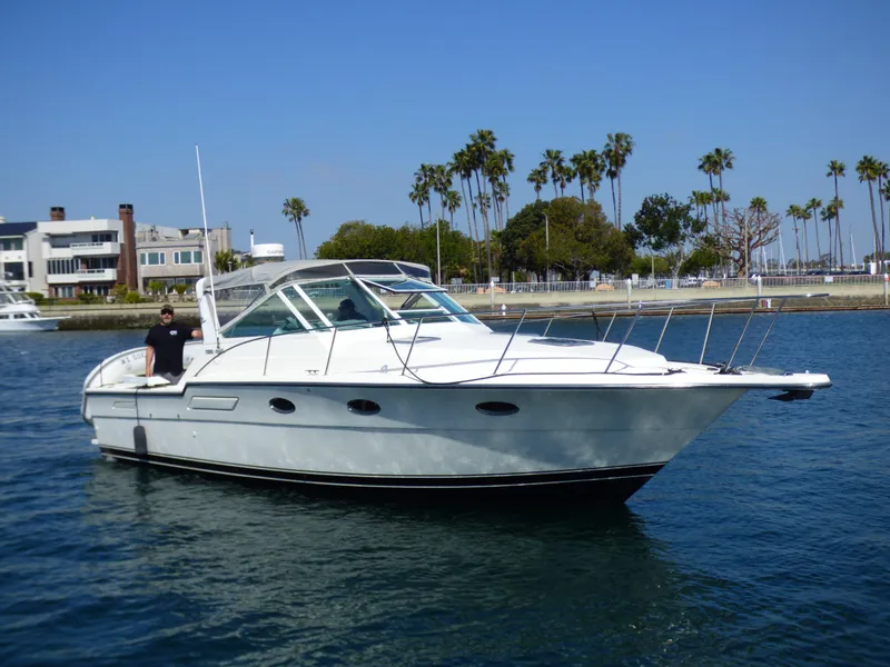 A 1989 Tiara Yachts 3300 Open cruising on calm water, surrounded by palm trees.