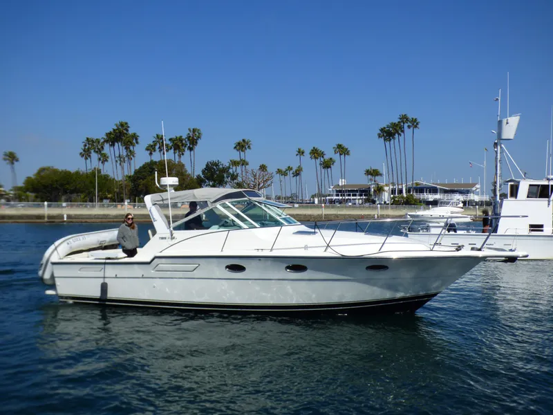 A white motorboat cruising on calm water, with palm trees in the background.
