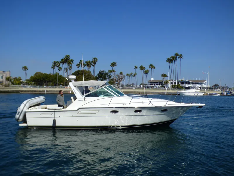 A 1989 Tiara Yachts 3300 Open cruising on calm water with palm trees in the background.