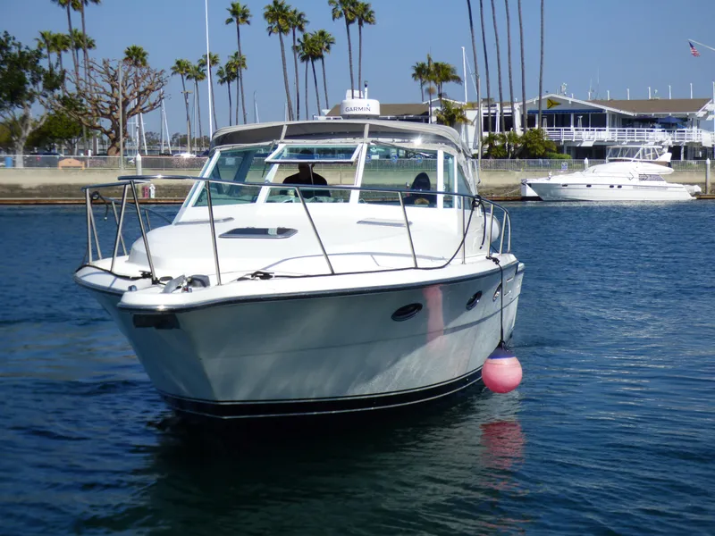 A 1989 Tiara Yachts 3300 Open cruising on calm water. Palm trees in the background.