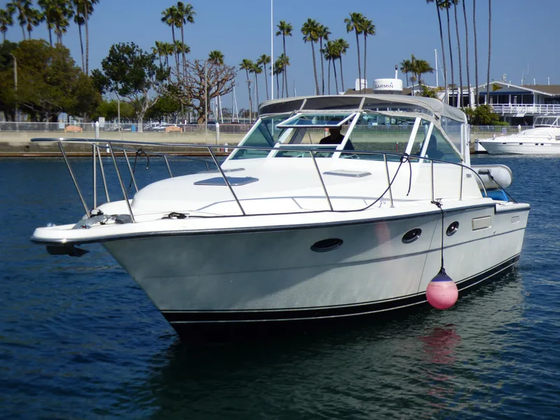 A 1989 Tiara Yachts 3300 Open is on the water, surrounded by palm trees.