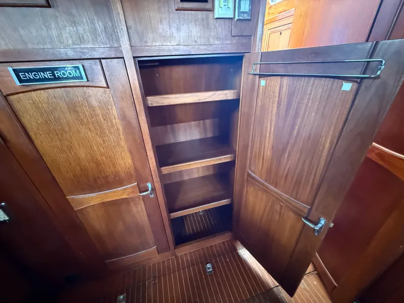 Wooden interior of 1985 Nauticat 43 yacht, featuring open storage shelves and engine room access.
