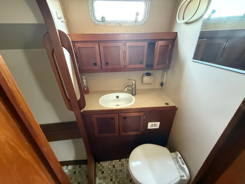 1985 Nauticat 43 yacht bathroom with wooden cabinets, sink, and toilet.