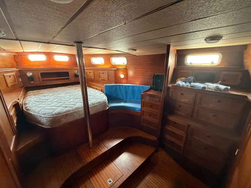 Cozy cabin interior of 1985 Nauticat 43 sailboat with bed, seating, and wooden storage.