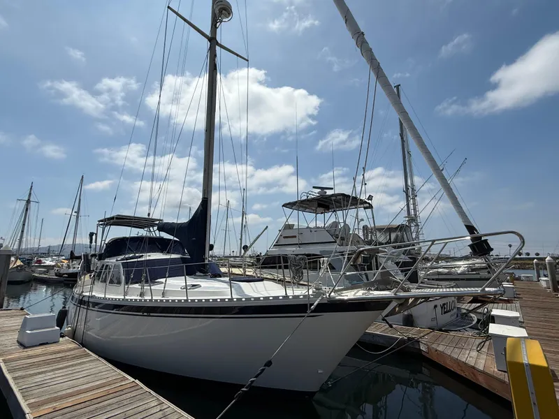1985 Nauticat 43 sailboat docked at marina under a partly cloudy sky.