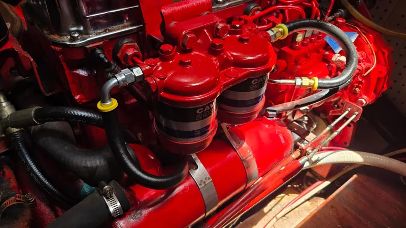 Engine components of a 1985 Nauticat 43, featuring red filters and hoses.