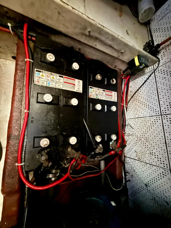 Battery compartment of a 1985 Nauticat 43 sailboat with red wiring connections.