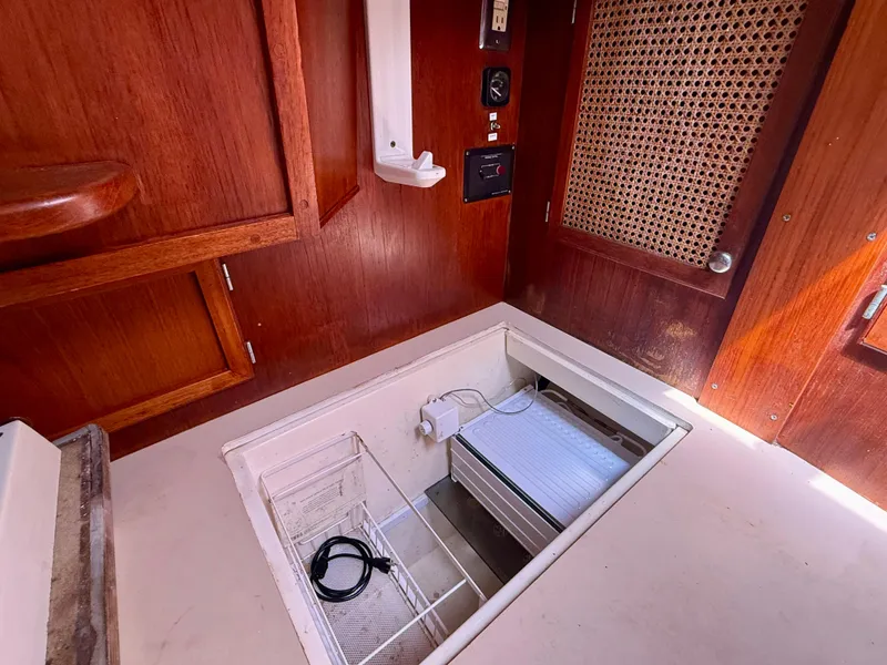 1985 Nauticat 43 interior with wooden cabinetry and open storage compartment.