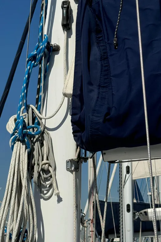 Close-up of 1989 Catalina Sloop sailboat mast with ropes and blue cover.