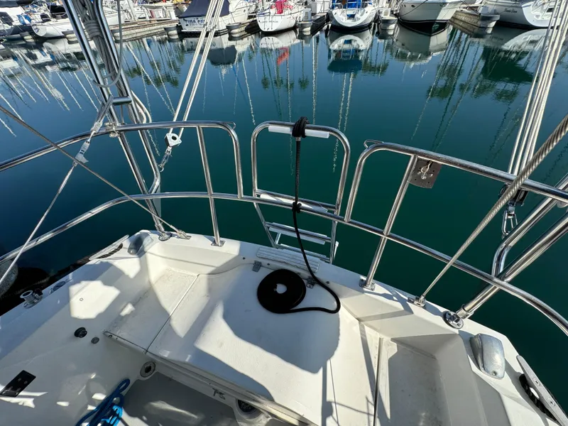 1989 Catalina Sloop sailboat deck with marina view, featuring stainless steel railings and calm water reflections.
