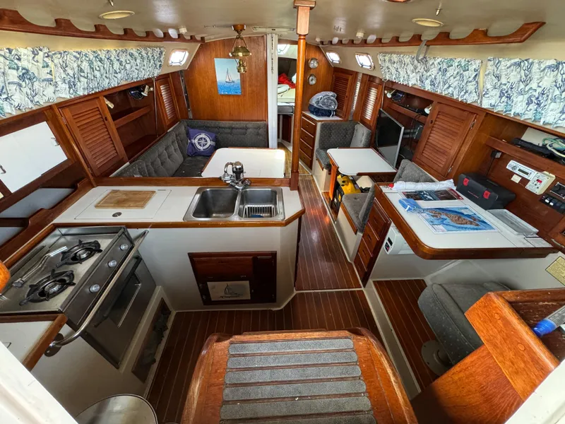 Interior of a 1989 Catalina Sloop sailboat with kitchen, seating, and wooden accents.