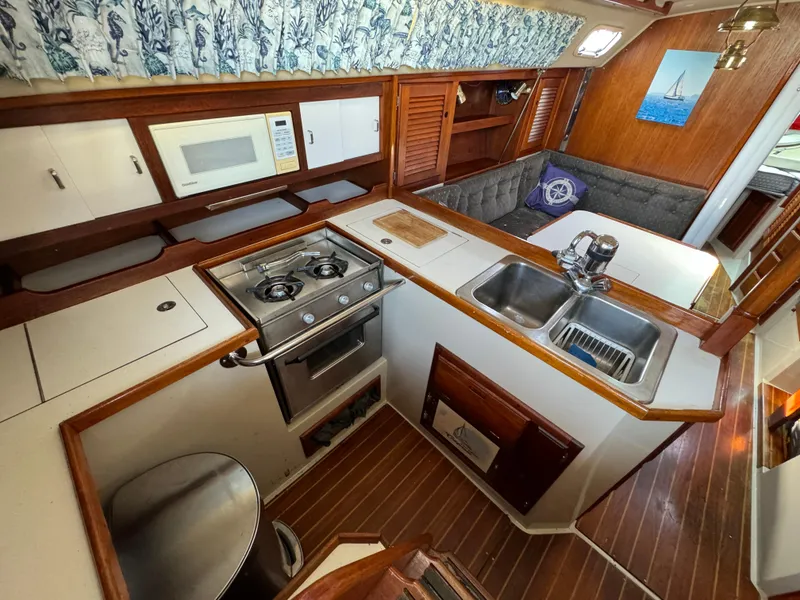 Interior of 1989 Catalina Sloop with kitchen, stove, sink, and seating area.
