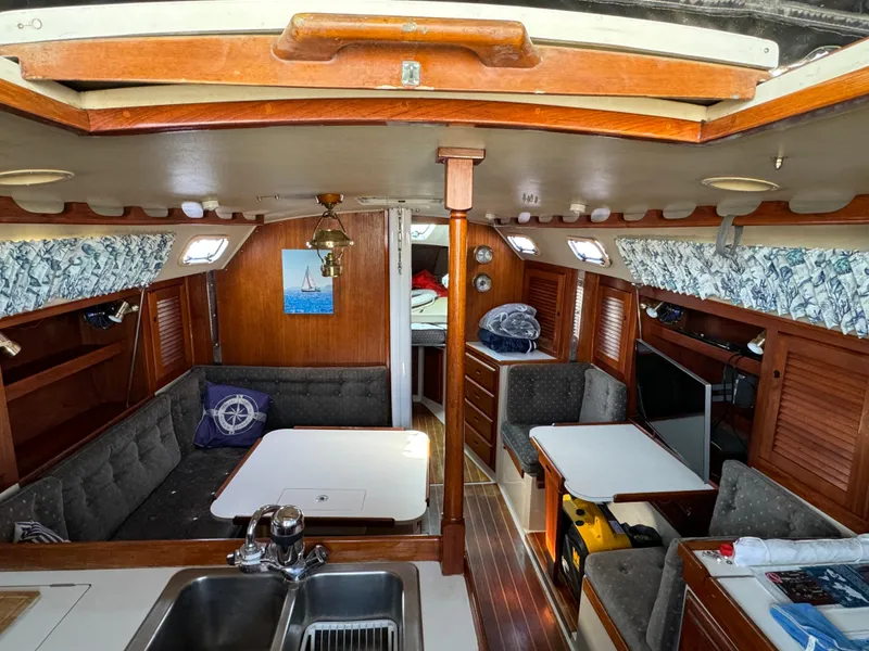 Interior of a 1989 Catalina Sloop sailboat featuring a cozy cabin with seating and a kitchenette.