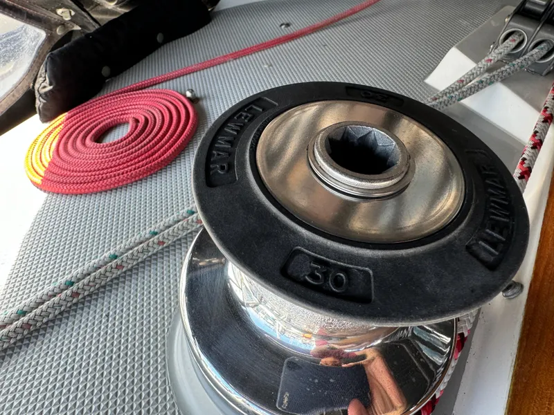 Winch on 1989 Catalina Sloop sailboat deck with coiled red rope.