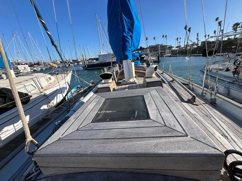 Sailboat deck view, Baba 30 model, 1977, docked in a marina with clear blue skies.