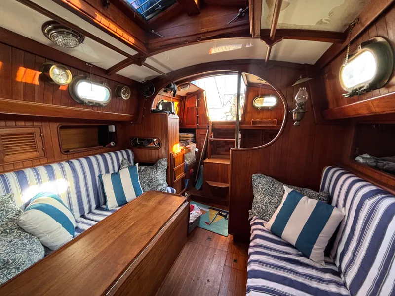 Interior of a 1977 Baba 30 sailboat with striped cushions and wooden finishes.