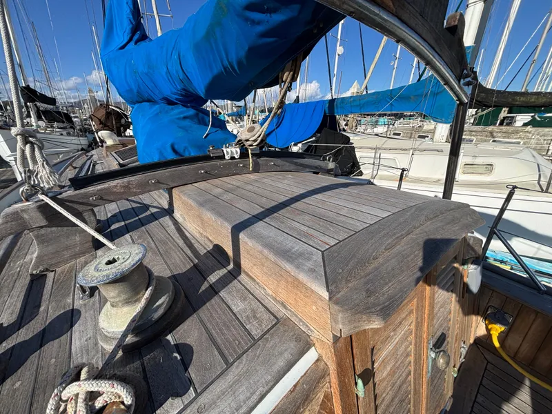 1977 Baba 30 sailboat deck with wooden details and blue sail cover in marina.