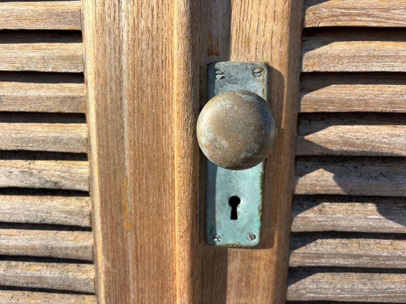 Vintage wooden door with a round metal doorknob and keyhole, Baba 30, 1977.