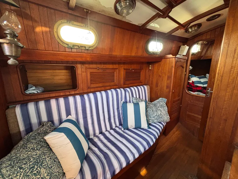 Cozy 1977 Baba 30 sailboat interior with striped cushions and wooden paneling.