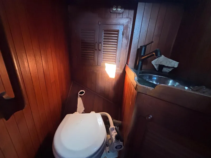1977 Baba 30 yacht bathroom with wooden paneling, toilet, and sink.