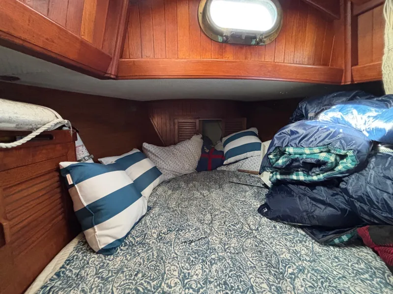 Cozy cabin interior of a 1977 Baba 30 sailboat with striped pillows and bedding.