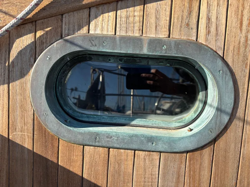 Porthole on a 1977 Baba 30 sailboat with wooden exterior.