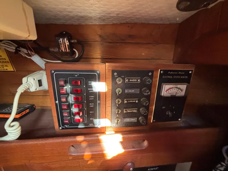 Electrical control panel inside a 1977 Baba 30 sailboat, featuring switches and a voltmeter.