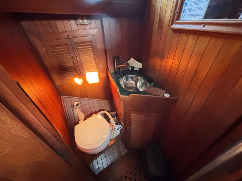 1977 Baba 30 sailboat bathroom with wooden interior, toilet, and sink.