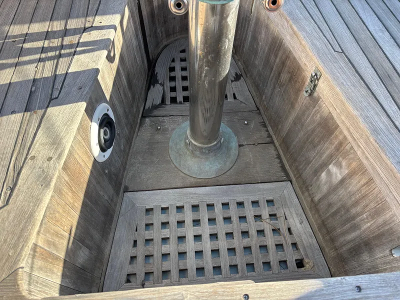 Wooden deck of 1977 Baba 30 sailboat with metal pole and grating.
