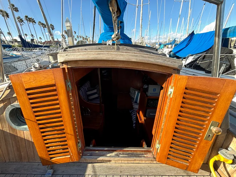 1977 Baba 30 sailboat with open wooden cabin doors, docked in a marina.