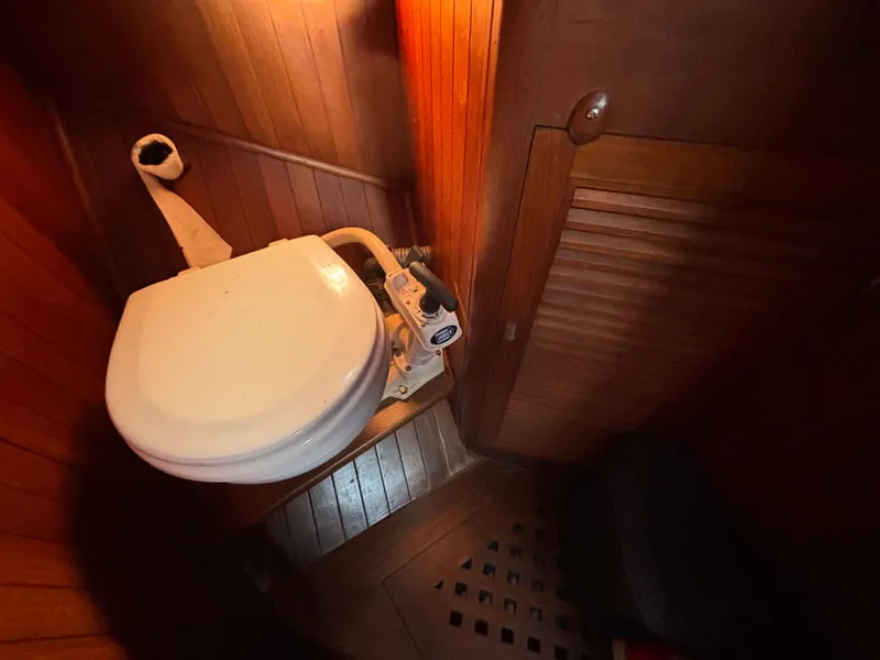 1977 Baba 30 sailboat bathroom with wooden interior and marine toilet.