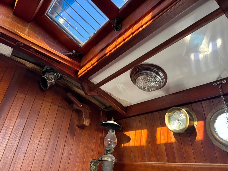 Interior of a 1977 Baba 30 sailboat with wooden paneling and nautical decor.