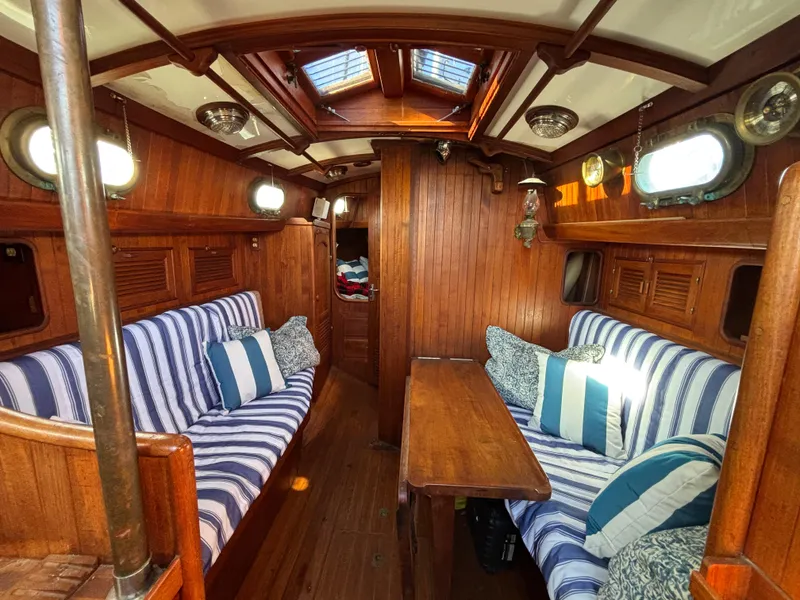 Cozy 1977 Baba 30 sailboat interior with wood paneling and striped cushions.
