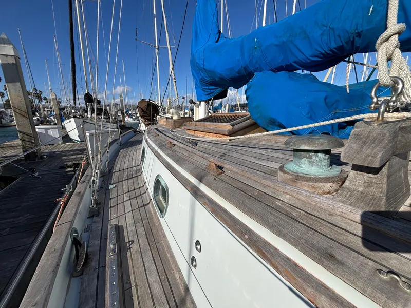Sailboat docked at marina, Baba 30 model, 1977, with blue sail cover and wooden deck.