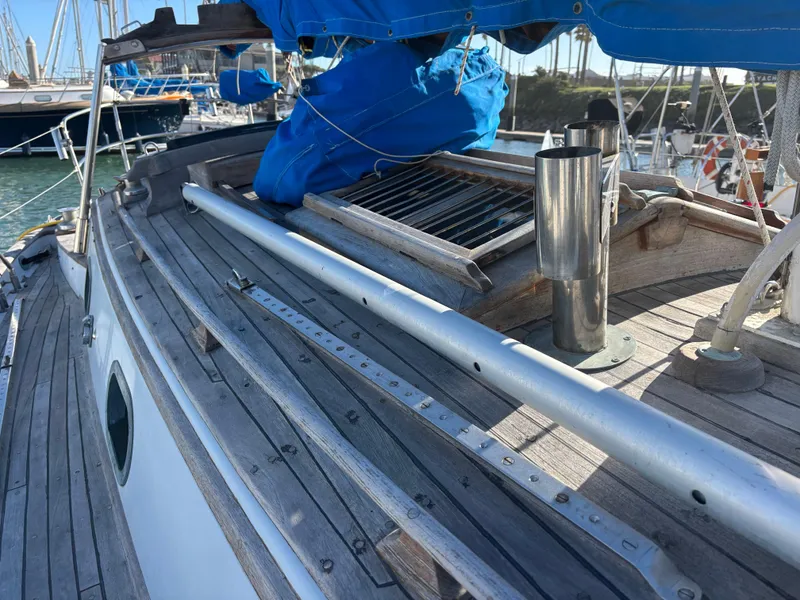 1977 Baba 30 sailboat deck with wooden finish and blue sail cover in marina.