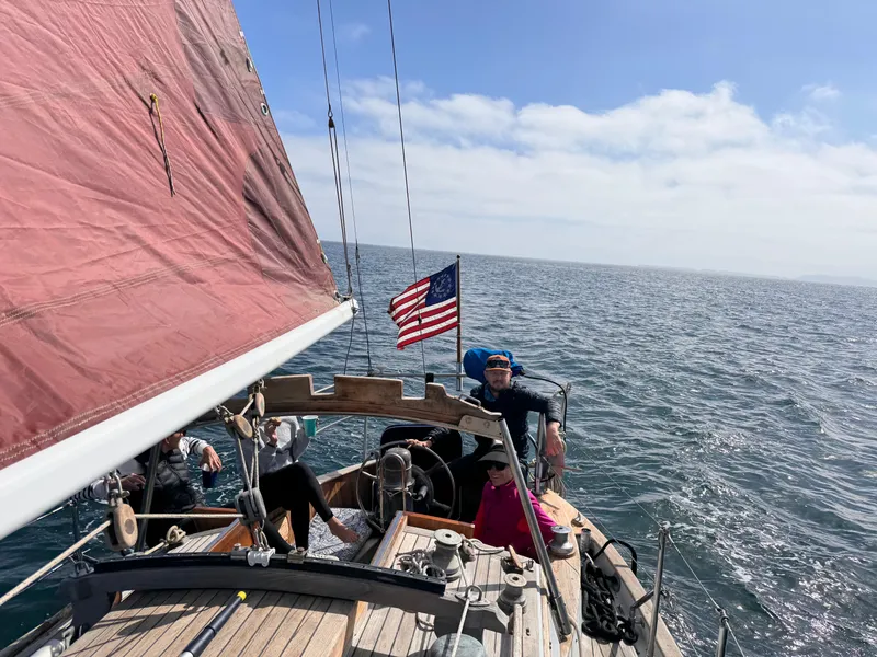 Sailing on a 1977 Baba 30 yacht with an American flag on open water.