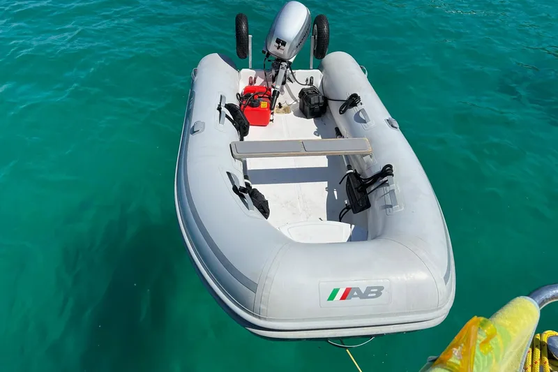 Inflatable boat with motor floating on clear turquoise water.