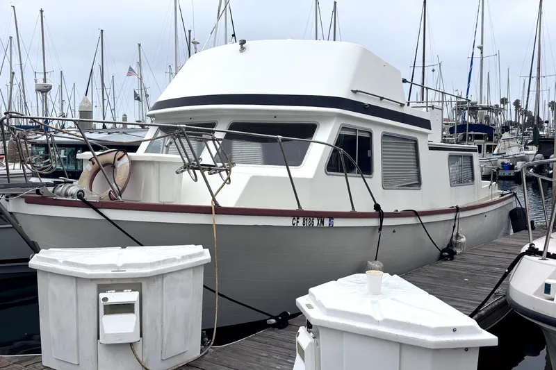 1974 Skookum 34 boat docked at marina with sailboats in background.