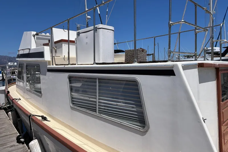 1974 Skookum 34 boat docked, featuring a white exterior and large windows.