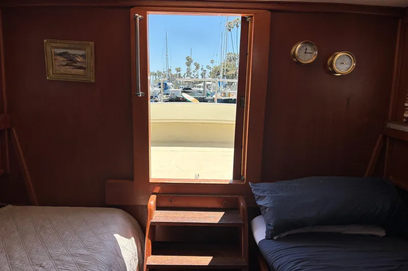 Interior of a 1974 Skookum 34 boat cabin with beds and a view outside.