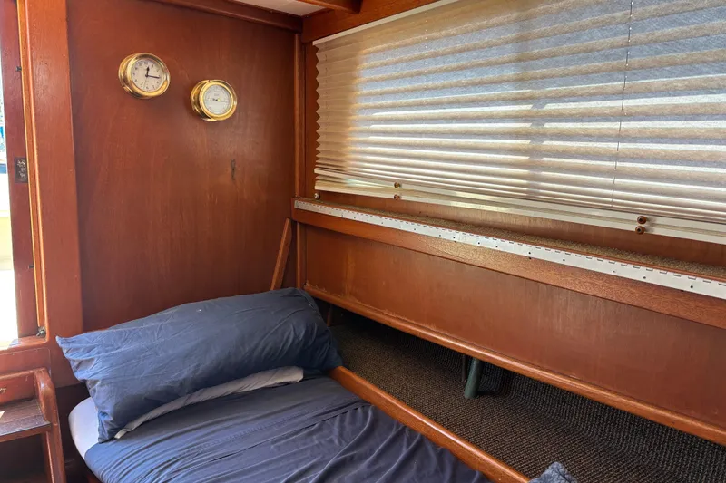 Cozy cabin interior of a 1974 Skookum 34 boat with wooden paneling and nautical instruments.
